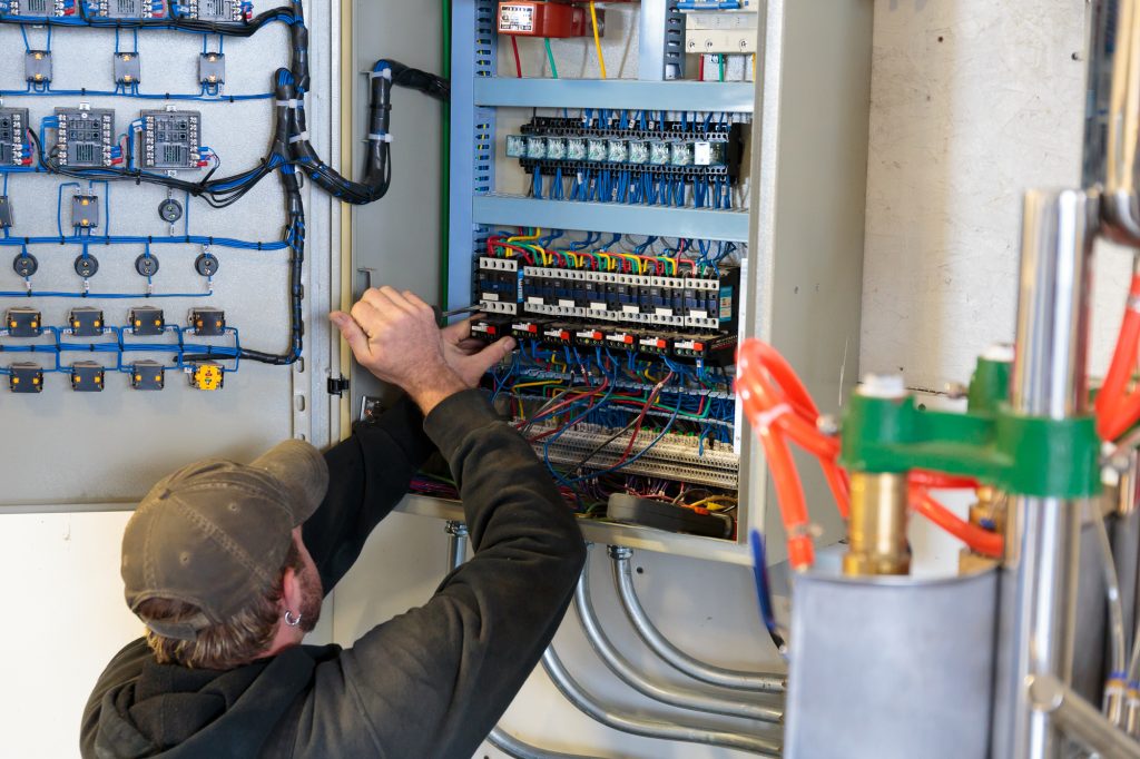 Electrician working on the service panel at a craft brewery commercial building.