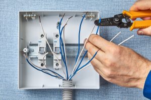 Electrician using wire stripper to prepare the panel outlet